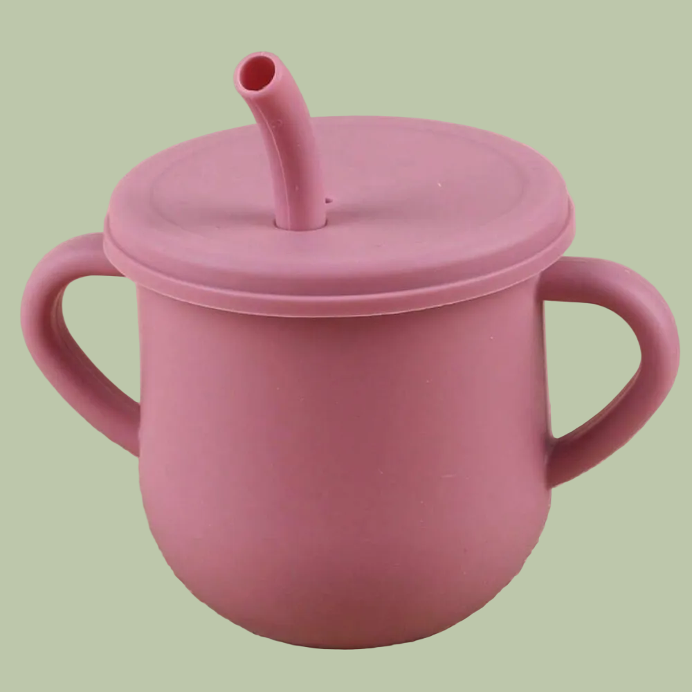 Pink cup with handles and a straw lid on a beige surface