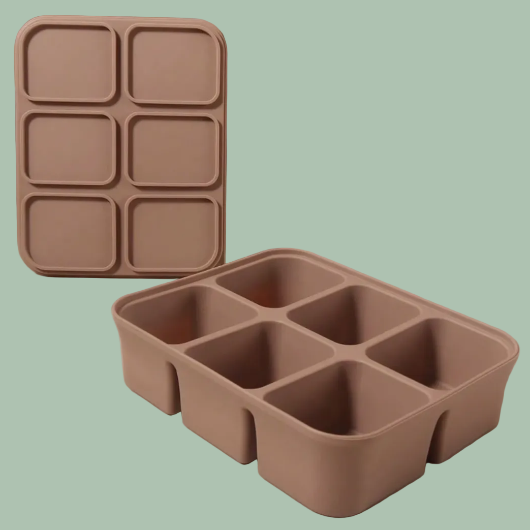 A six-compartment silicone tray in a muted taupe-brown color, shown both standing upright in the back and lying flat in the foreground on a clean beige surface against a matching beige background.