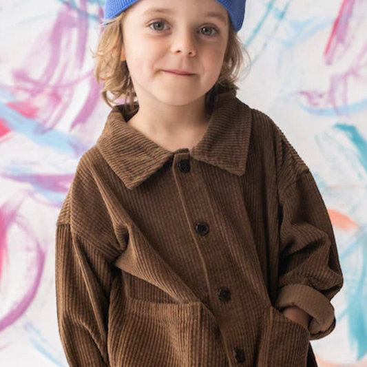 Child wearing a brown coat and blue beanie against a colorful abstract background