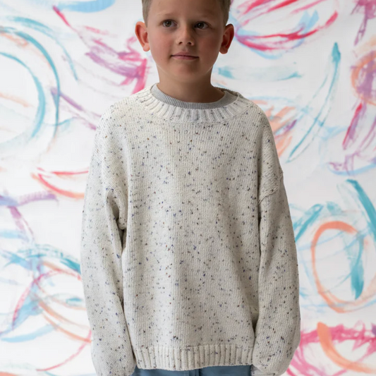 Child wearing a light gray sweater against a colorful abstract background