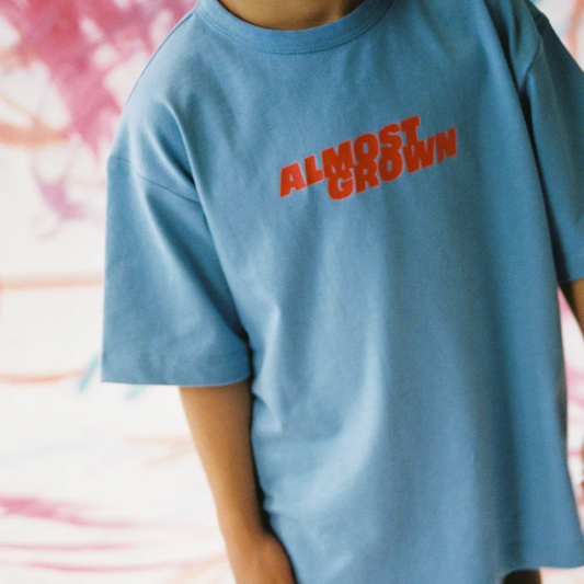 Person wearing a blue t-shirt with 'ALMOST GROWN' text in red.