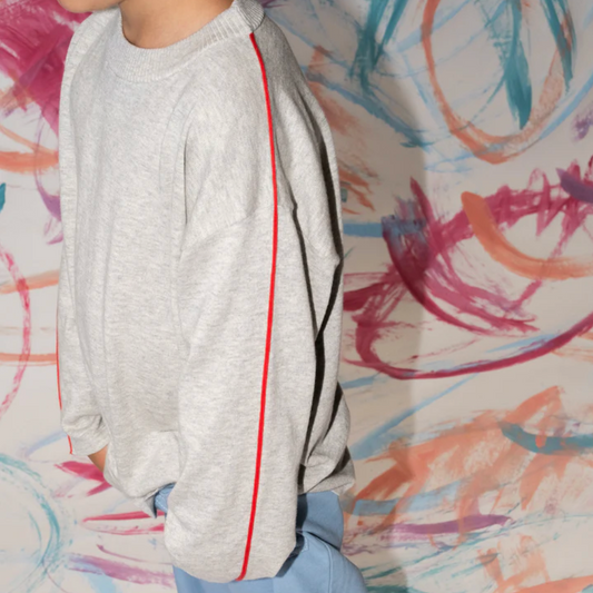 Person wearing a gray sweater with red and black accents against a colorful abstract background