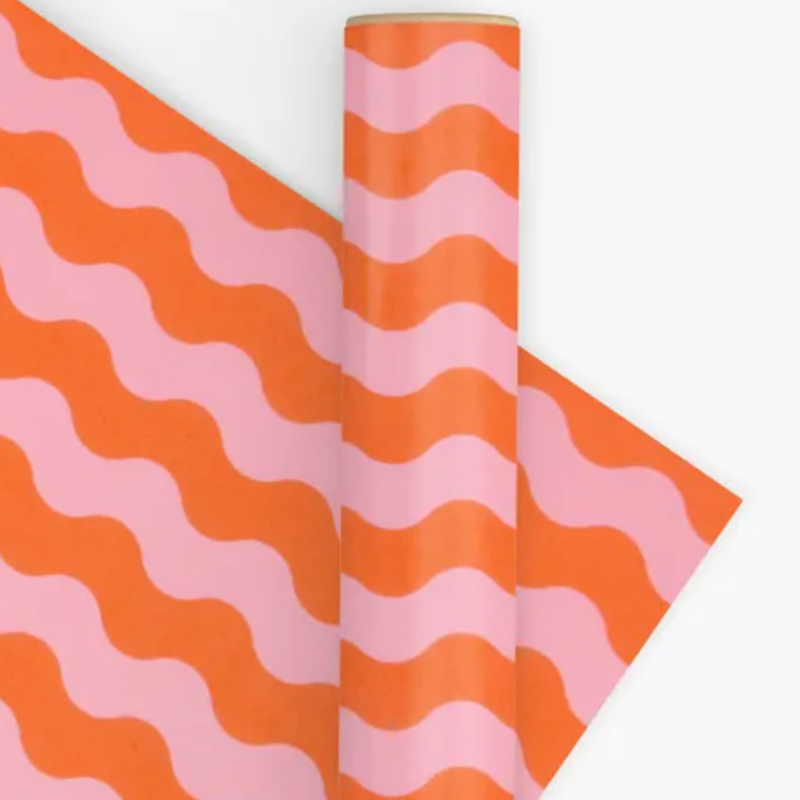 Roll of pink and orange wavy patterned paper on a white background