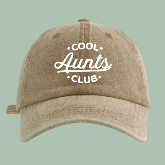 A washed tan baseball cap with white embroidered text reading 'COOL Aunts CLUB' on the front, shown against a plain white background.