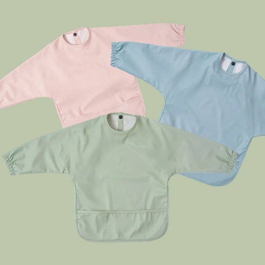 Three baby bibs in pink, blue, and green on a white background