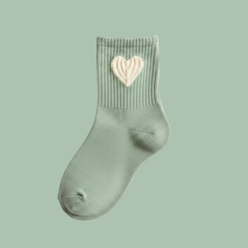 A single sage green ribbed ankle sock with a textured cream-colored heart motif on the cuff, displayed on a clean white background.