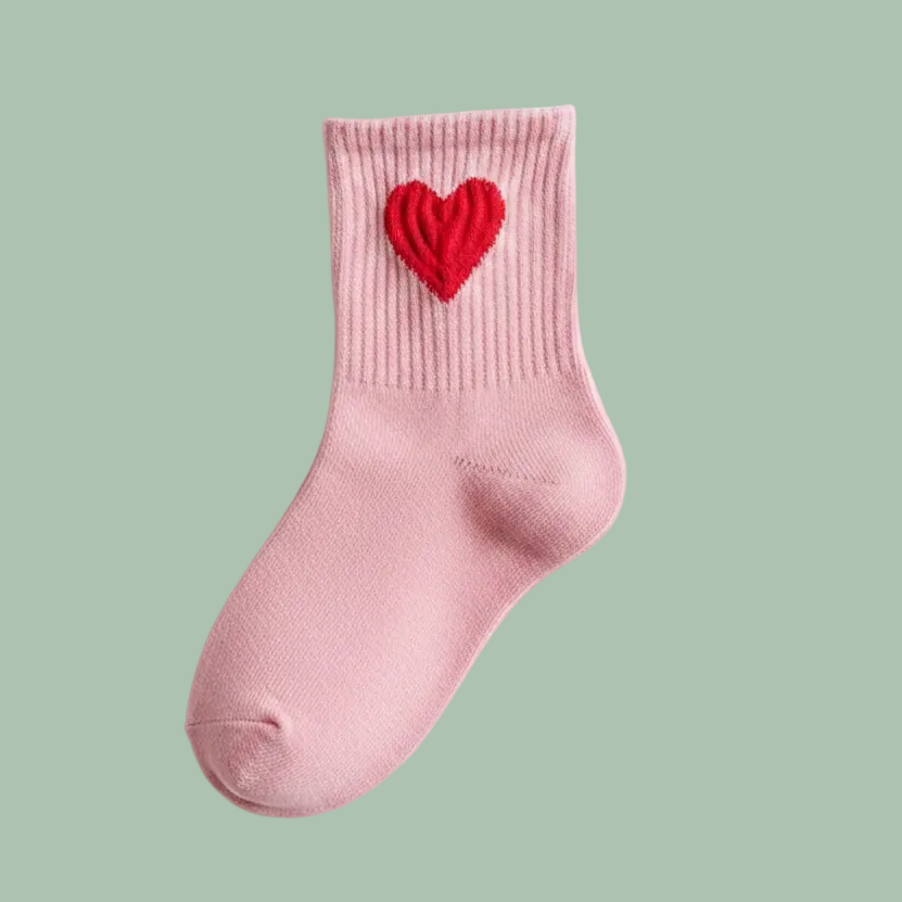 A single light pink ribbed knit sock with a textured red heart embroidered on the cuff, shown on a clean white background.