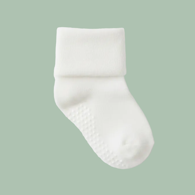 A white pair of baby socks on a green background