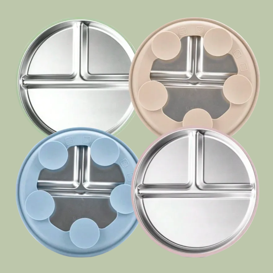 Four round stainless steel divided plates in different colors on a white background
