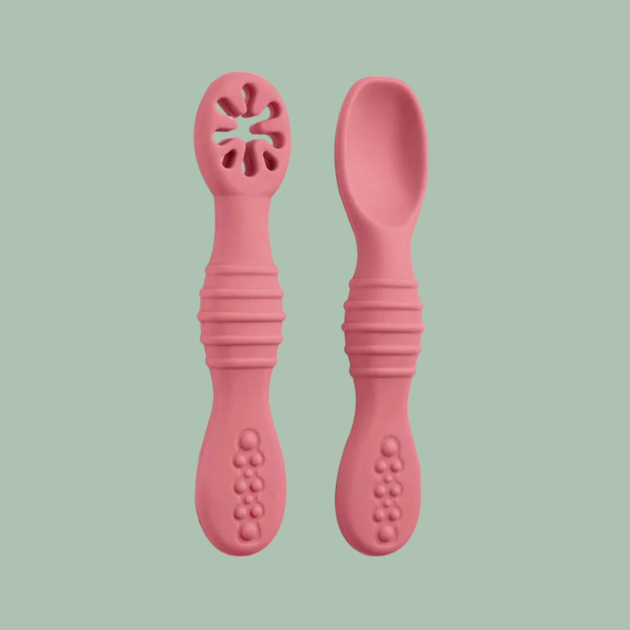 Two pink silicone baby feeding tools, one with a flower-shaped spout and one with a rounded spoon bowl, shown on a plain white background.