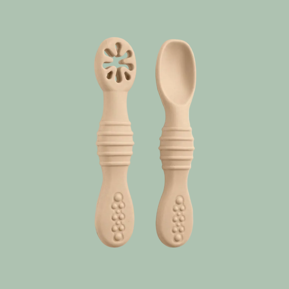 Two beige silicone baby feeding utensils, one a spork with a flower-shaped opening at the tip and one a spoon, shown on a plain white background.