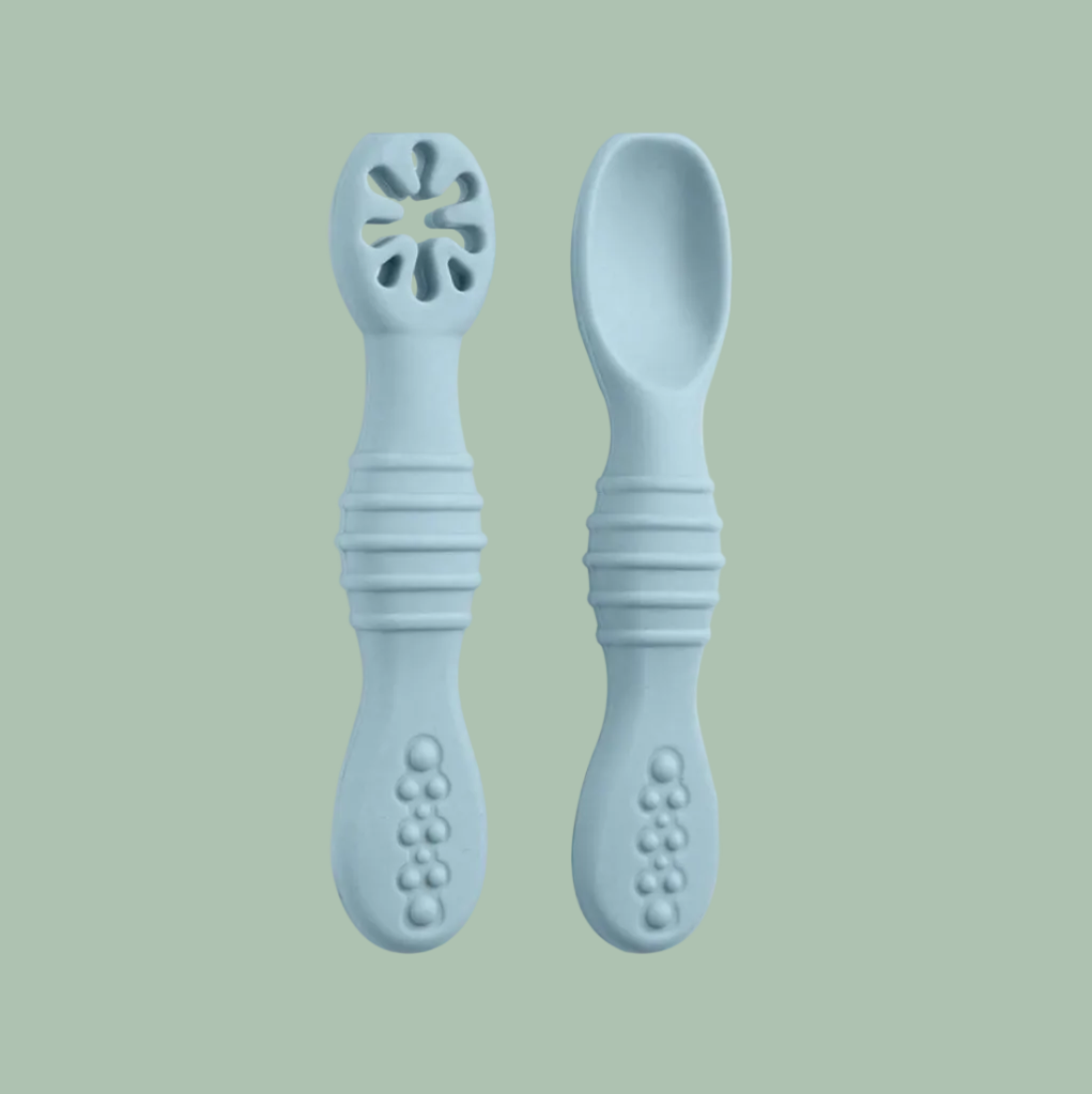 A pair of baby silicone feeding utensils, including a teething spoon with a flower-shaped opening and a regular spoon, in a light pastel blue color, shown on a plain white background.